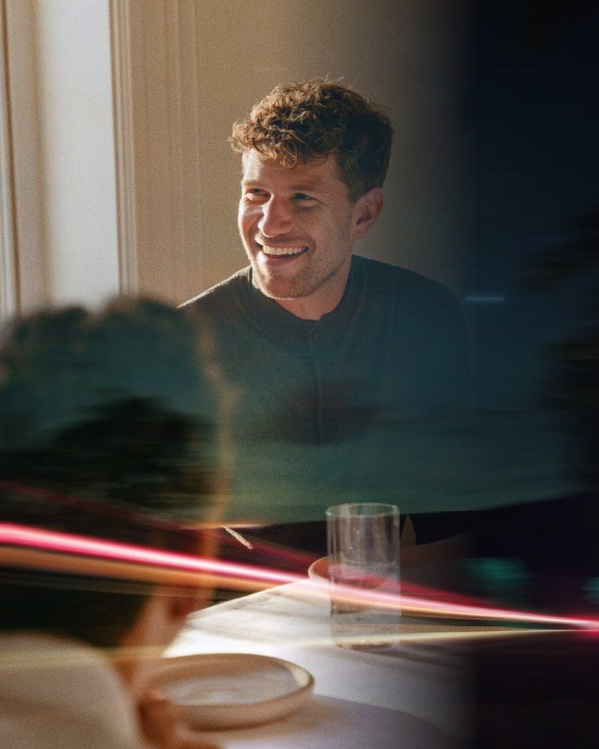 A man smiling across a dinner table