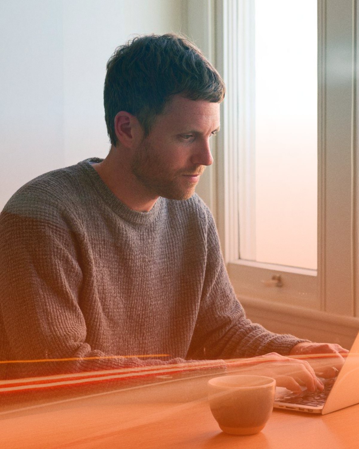 A rep working at a laptop by a window, with streaks of light passing in front