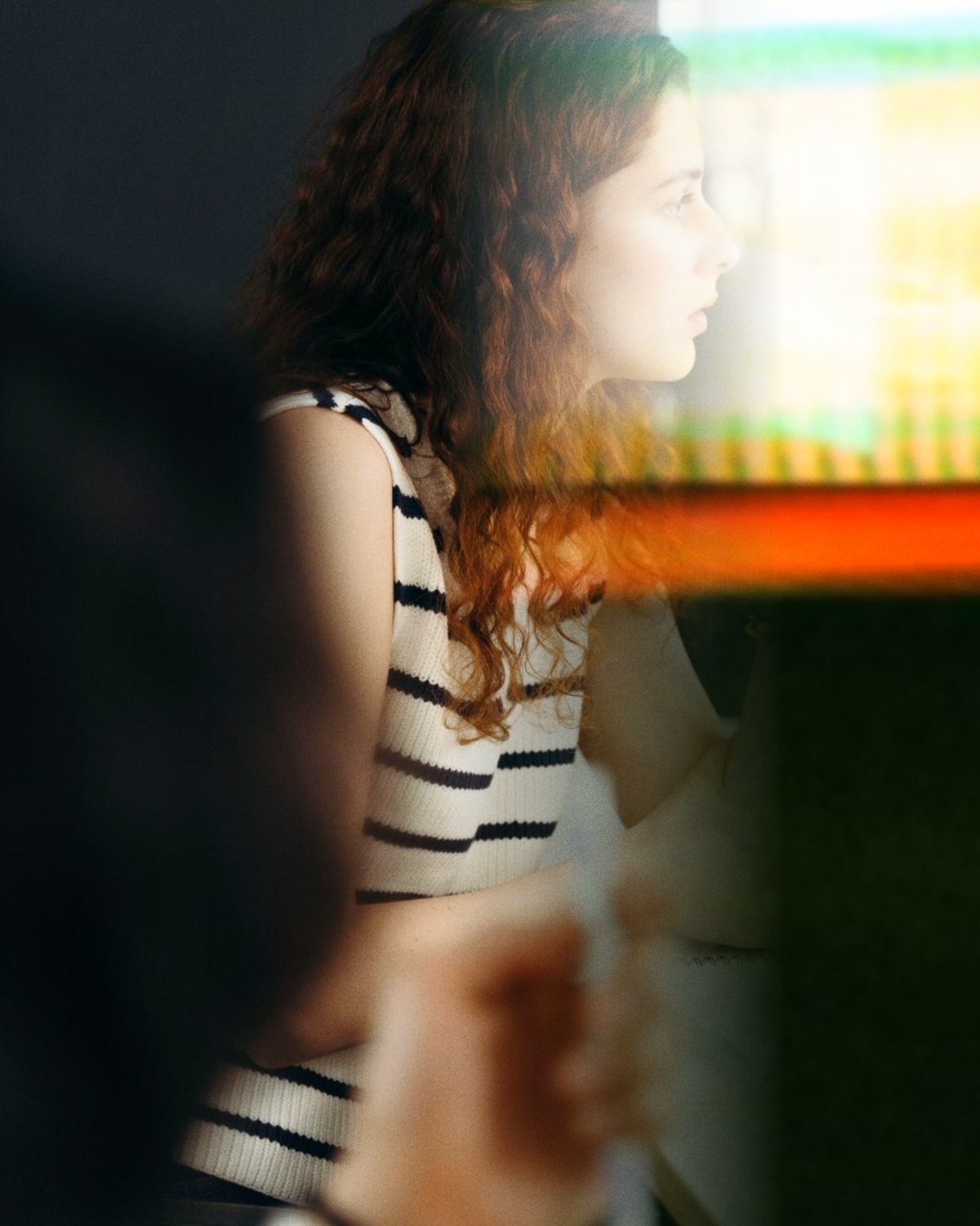 A woman in profile at her desk, watching her screen, with a band of warm light passing in front